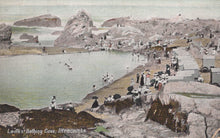 Load image into Gallery viewer, Vintage postcard of a coastal scene with people at a bathing cove, featuring rocky terrain and a body of water.