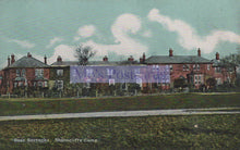 Load image into Gallery viewer, Vintage postcard of a row of houses with a banner in the center, set against a blue sky.