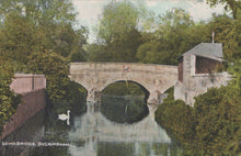 Load image into Gallery viewer, Vintage-style image of a stone bridge over water with trees and a building on the right.