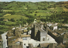 Load image into Gallery viewer, Aerial view of a town with a prominent church in the center, surrounded by green fields.