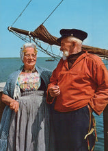Load image into Gallery viewer, Two people standing on a dock with a sailboat in the background