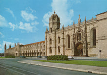 Load image into Gallery viewer, Large stone building with architectural details under a blue sky