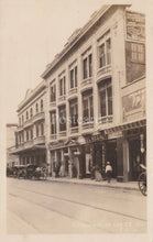 Load image into Gallery viewer, Vintage black and white photo of a street scene with a building and people on a sidewalk.