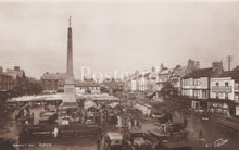 Load image into Gallery viewer, Vintage black and white photo of a town square with a central obelisk and market stalls.