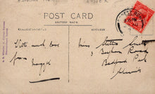 Load image into Gallery viewer, Vintage postcard with handwritten text and a red stamp on a brown background