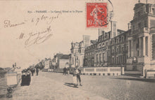 Load image into Gallery viewer, Vintage postcard of a street scene with a large building and people walking, featuring a red stamp.