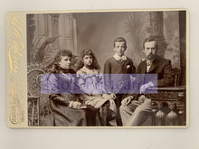 Load image into Gallery viewer, Vintage family portrait with four individuals in formal attire, sitting together.