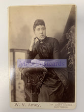 Load image into Gallery viewer, Vintage photograph of a woman sitting on a decorative chair with 'W. V. Amey' branding.