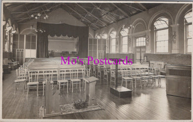 Vintage black and white photo of a large room with rows of chairs and a stage, labeled 'Mo's Postcards'.
