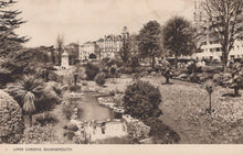 Load image into Gallery viewer, Vintage black and white photograph of Upper Gardens in Bournemouth with buildings in the background.
