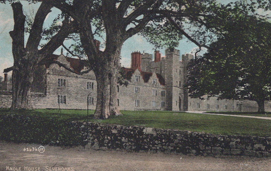 Historic building with red brick chimneys, surrounded by trees and greenery.