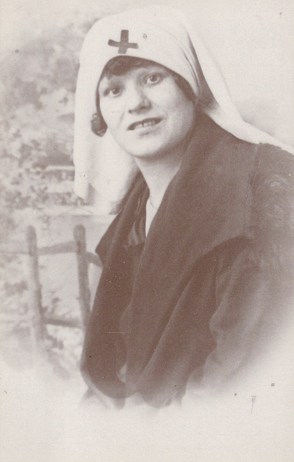 Vintage postcard of a woman wearing a headscarf with a cross emblem.