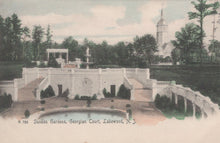 Load image into Gallery viewer, Vintage postcard of Sunken Gardens at Georgian Court in Lakewood, NJ with a church in the background.
