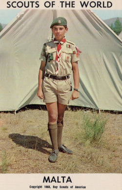 Scout in uniform standing in front of a tent with 'Scouts of the World' and 'Malta' text.