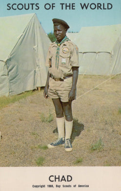 Scout in uniform standing in front of tents with 'Scouts of the World' and 'Chad' text at the top.