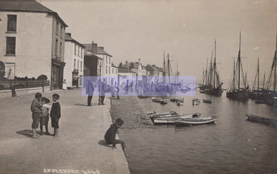 Vintage photograph of children by a harbor with boats and buildings in the background