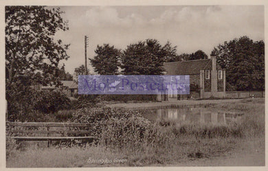 Vintage black and white photo of a pond with trees and buildings in the background