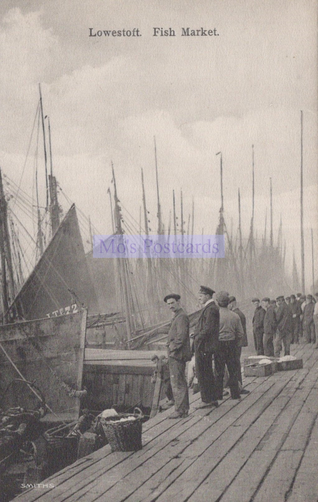 Vintage black and white photograph of a fish market in Lowestoft with people and boats.