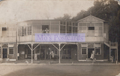 Vintage black and white photo of a two-story building with people on the porch and around the front door.