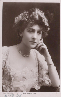 Vintage photograph of a woman in formal attire with jewelry, against a dark background.