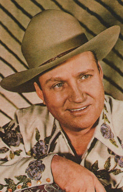Man wearing a wide-brimmed hat and patterned shirt against a striped background