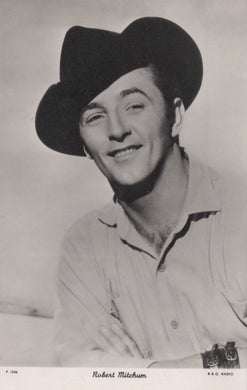 Black and white portrait of a man wearing a cowboy hat and shirt, with a camera around his neck.