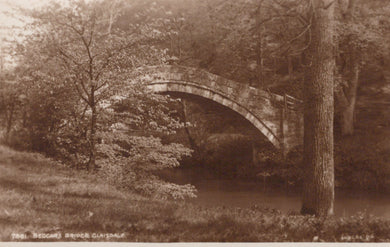 Vintage photograph of a stone bridge over a stream with trees on either side.
