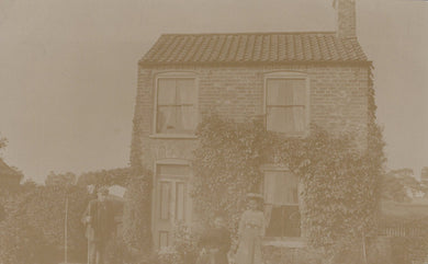 Vintage sepia-toned photograph of a two-story house with people in front