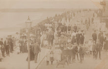 Load image into Gallery viewer, Vintage photograph of a crowded outdoor scene with people and a dog.

