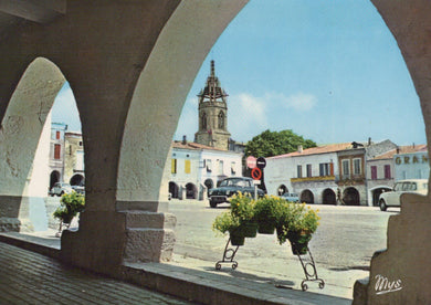 Town square with a clock tower and arches, featuring a cart with plants.