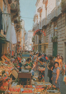 Busy street market with people and produce in an urban setting
