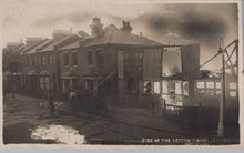 Load image into Gallery viewer, Burnt-out building with surrounding houses in a residential area, likely after a fire.
