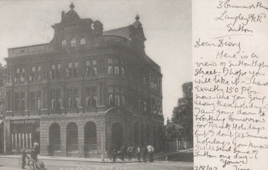 Vintage black and white photo of a large building with people in front, handwritten text on the right.