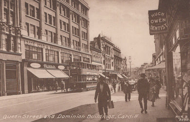 Vintage black and white photograph of a city street with pedestrians and shops in Cardiff.
