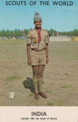 Scout in uniform with a badge, standing outdoors with 'Scouts of the World' text at the top.