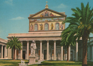 Historic building with columns and statues, palm trees, and a blue sky.