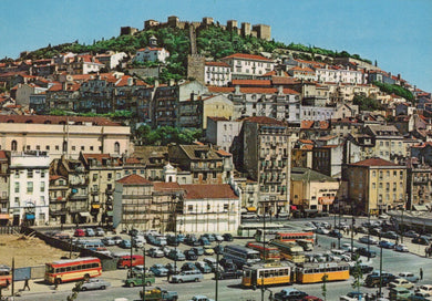 Cityscape with historical castle on a hill, buildings, and vehicles on a street.