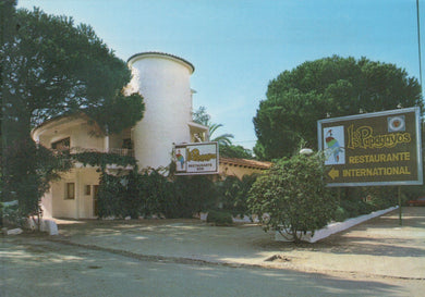 White building with a sign in front on a clear day
