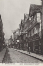 Load image into Gallery viewer, Vintage black and white street scene with traditional buildings and a person walking on a cobbled street.
