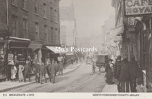 Load image into Gallery viewer, Vintage black and white photo of a street scene with people and shops 
