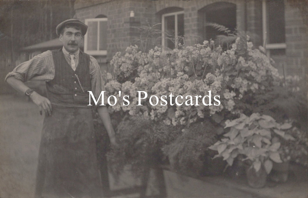 Vintage photo of a man standing in front of a building with plants 
