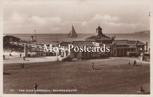Load image into Gallery viewer, Vintage black and white postcard of a pier approach with a sailboat and buildings.
