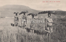 Load image into Gallery viewer, Zulu women carrying wood on their heads in a grassy field with mountains in the background.
