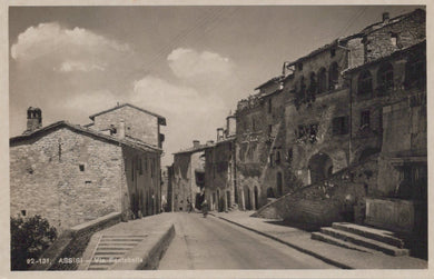Vintage black and white photo of a street in a small town with stone buildings.