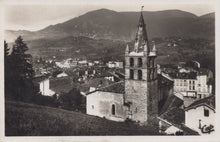 Load image into Gallery viewer, Vintage black and white photo of a town with a prominent clock tower and mountains in the background.

