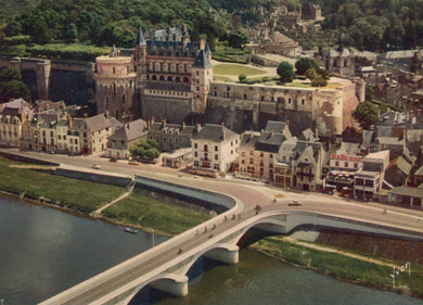 Aerial view of a historic castle with surrounding buildings and a bridge over water.
