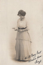 Load image into Gallery viewer, Vintage black and white photograph of a woman holding a small object, with text at the bottom.
