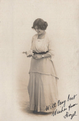 Vintage black and white photograph of a woman holding a small object, with text at the bottom.