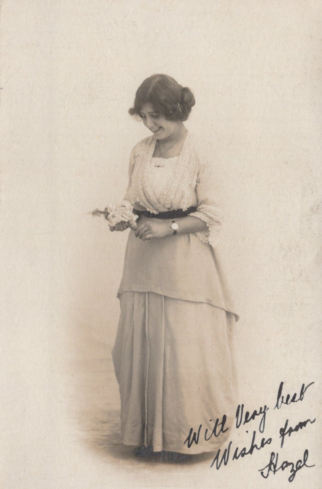Vintage black and white photograph of a woman holding a small object, with text at the bottom.
