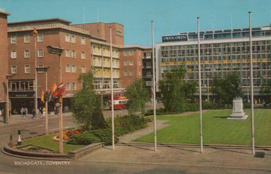 Vintage photograph of a city square with buildings, flags, and greenery.